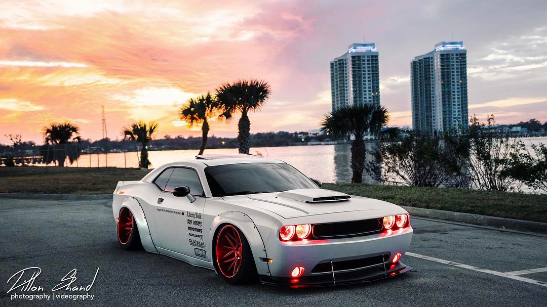 Three quarters view of a white Dodge Challenger with red LED headlight and fog light halo rings installed.