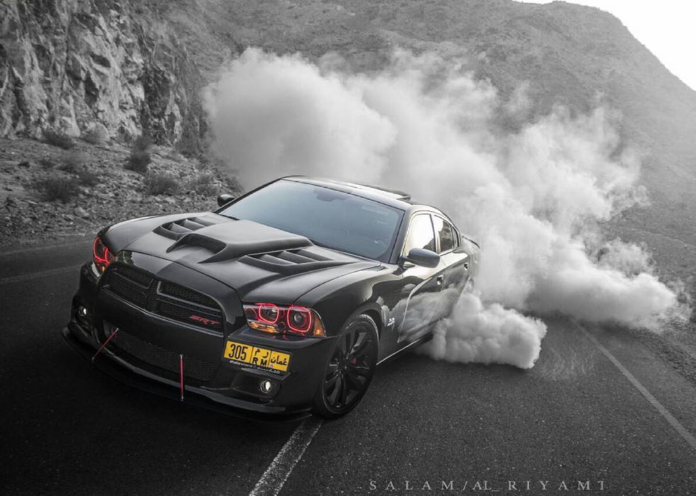 Three quarters view of a black Dodge Charger with red LED headlight halo rings installed.