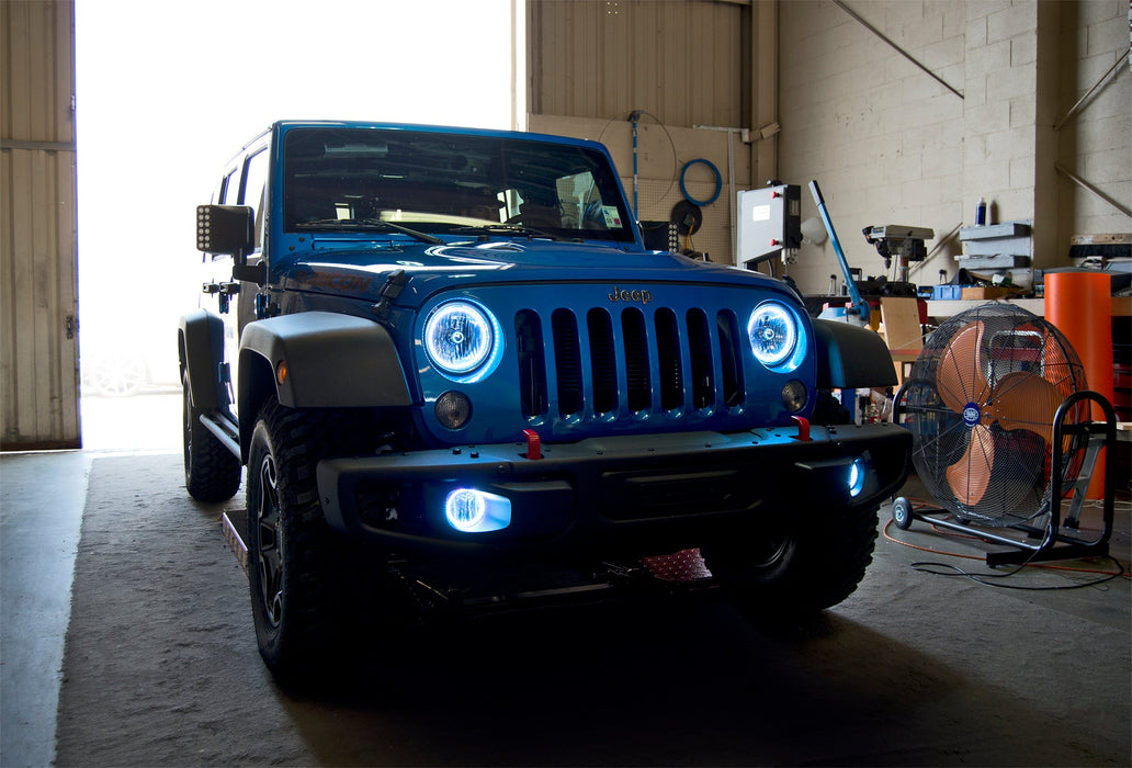 Three quarters view of a Jeep Wrangler JK with white LED headlight and fog light halo rings installed.