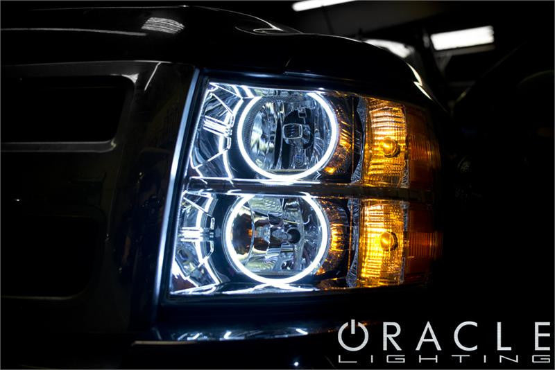 Close-up of white LED headlight halo rings installed on a Chevrolet Silverado.