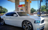 White charger at a gas station with blue halo headlights.