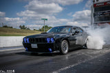 Three quarters view of a black Dodge Challenger with blue LED headlight and fog light halo rings installed.