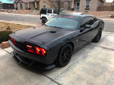 Three quarters view of a black Dodge Challenger with red LED headlight halo rings installed.