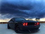 Three quarters view of a black Dodge Challenger with red LED headlight halo rings installed.