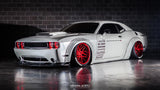 Three quarters view of a white Dodge Challenger with red LED headlight halo rings installed.