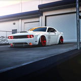 Three quarters view of a white Dodge Challenger with red LED headlight and fog light halo rings installed.