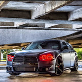 Three quarters view of a black Dodge Charger with red LED headlight halo rings installed.