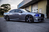 Three quarters view of a silver Dodge Charger with blue LED headlight halo rings.