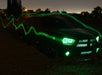 Three quarters view of a black Dodge Charger with green LED headlight and fog light halo rings installed.