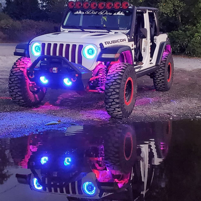 A white Jeep Gladiator with multiple aftermarket lighting prodcuts installed, including Oculus Headlights, fog light halos, and rock lights.
