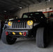 Front end of a Jeep Wrangler JK with yellow LED headlight and fog light halos installed.