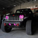 Front end of a Jeep Wrangler JK with pink LED headlight and fog light halos installed.