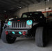Front end of a Jeep Wrangler JK with cyan LED headlight and fog light halos installed.