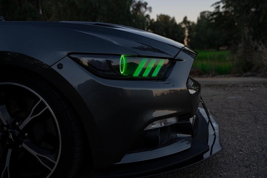 Close-up of a Ford Mustang headlight with green halos and DRLs.