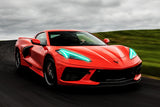 Three quarters view of a red C8 Corvette rolling with green headlight DRLs.