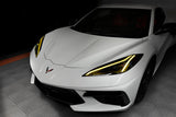 Front end of a white C8 Corvette with yellow headlight DRLs.