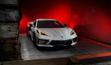 Three quarters view of a white C8 Corvette with amber headlight DRLs.