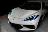 Front end of a white C8 Corvette with cyan headlight DRLs.