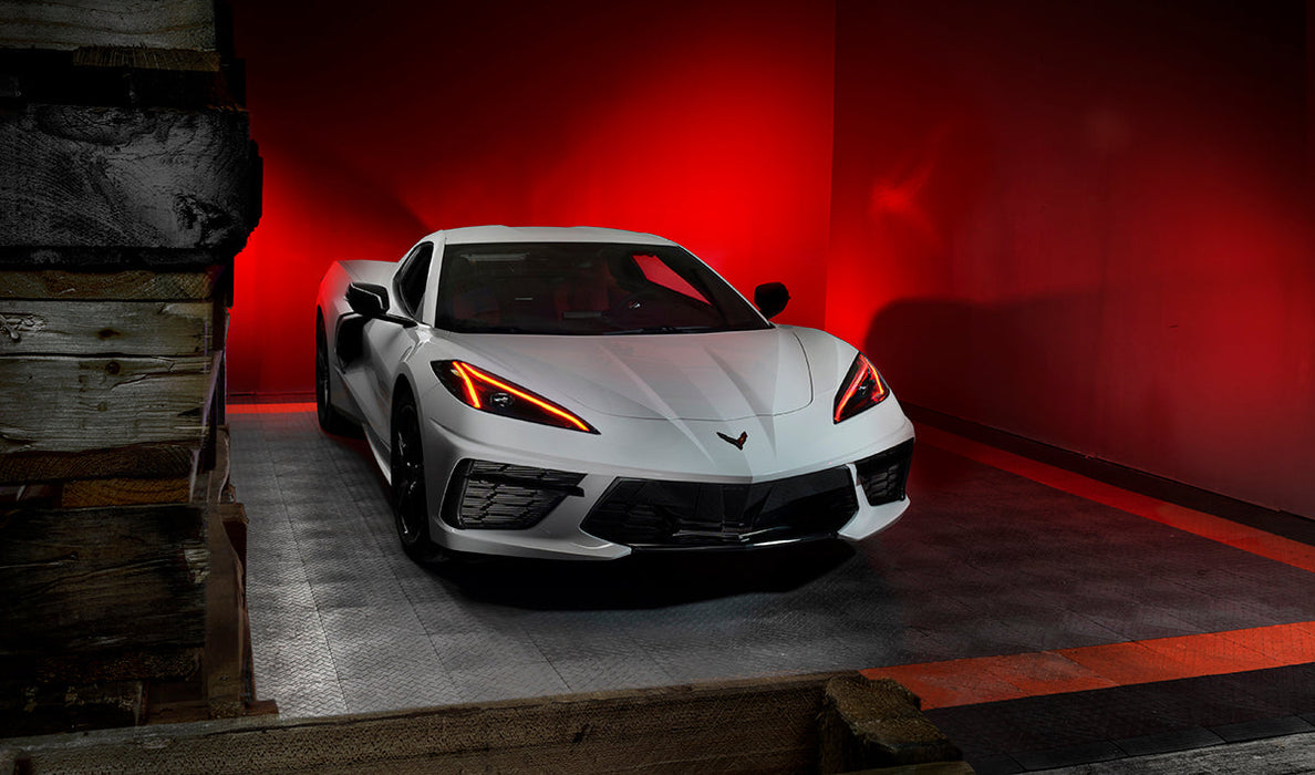 Three quarters view of a white C8 Corvette with red headlight DRLs.