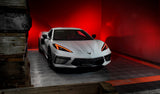 Three quarters view of a white C8 Corvette with red headlight DRLs.