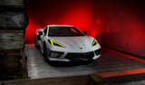 Three quarters view of a white C8 Corvette with yellow headlight DRLs.