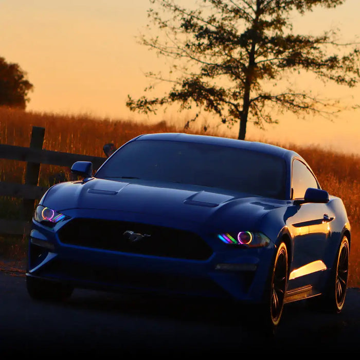 Ford Mustang driving outside with rainbow LED headlights.