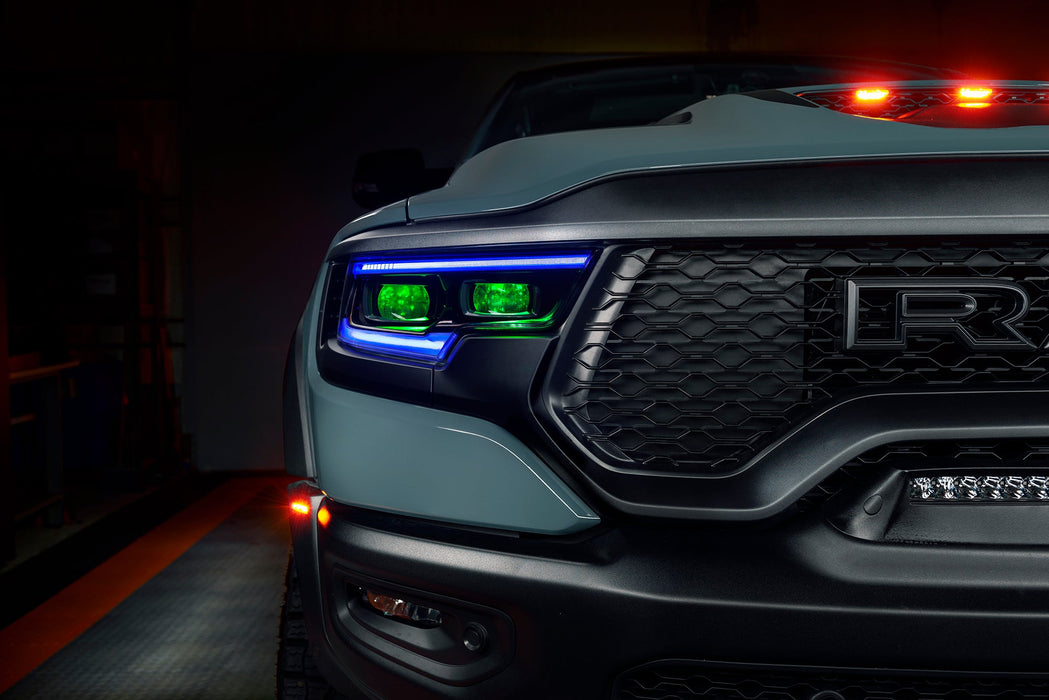Close-up of Ram 1500 headlights with blue DRLs and green demon eye projectors.