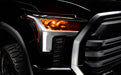 Close-up of a 2022+ Toyota Tundra headlight module installed with amber demon eye projector.