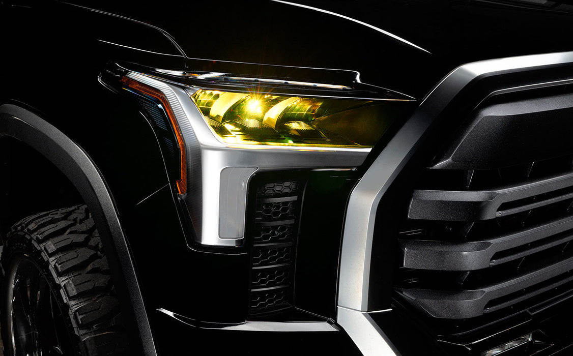 Close-up of a 2022+ Toyota Tundra headlight module installed with yellow demon eye projector.