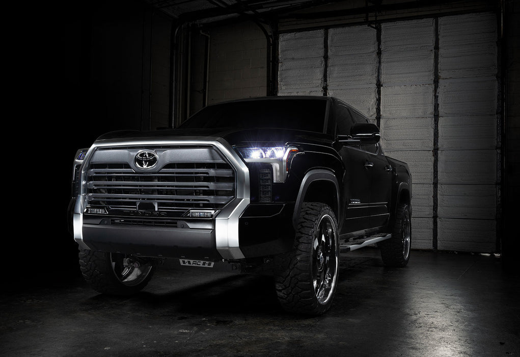 Three quarters view of a black Toyota Tundra with white demon eye projectors.