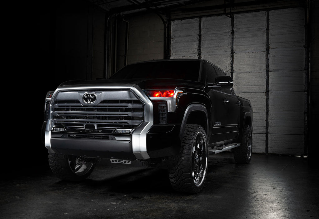 Three quarters view of a black Toyota Tundra with red demon eye projectors.