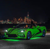 Three quarters view of a green C8 Corvette with green headlight DRLs.