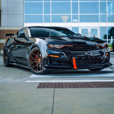 Three quarters view of a black Chevrolet Camaro with amber headlight and fog light DRLs.