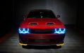 Front view of a red Dodge Challenger with cyan LED headlight halo rings installed.