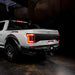 Rear three quarters view of white Ford Raptor with brake lights on
