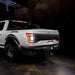 Rear three quarters view of white Ford Raptor with reverse lights on