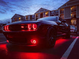 Three quarters view of a Dodge Challenger with red headlight and fog light halos.