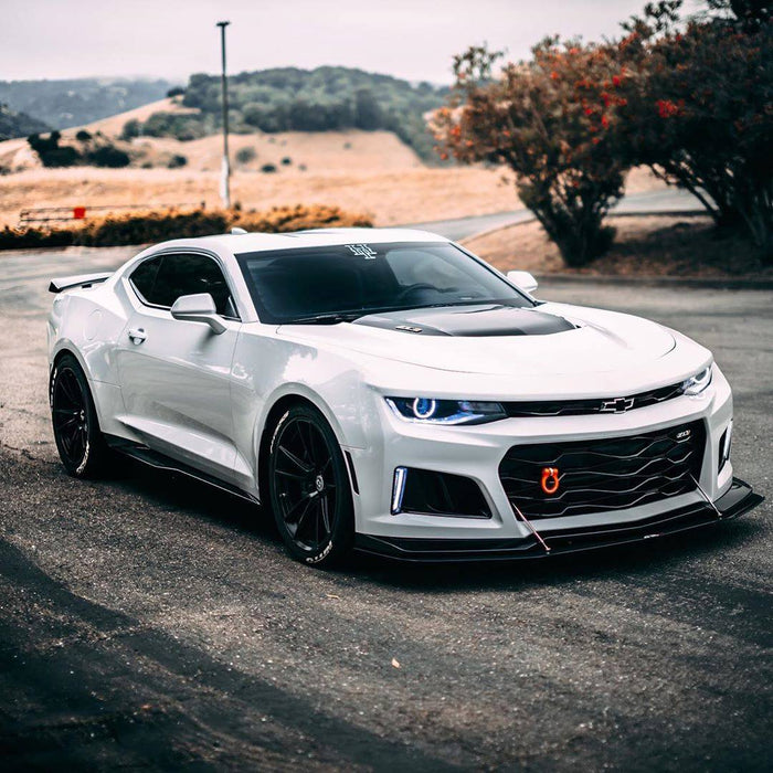 Three quarters view of a white Chevy Camaro with white projector halos.