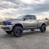 Three quarters view of a silver RAM 1500 with blue headlight halos.