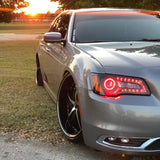 Front end of a Chrysler with red LED headlight halo rings installed.