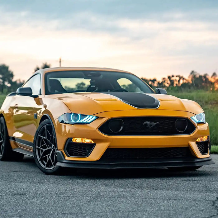 Three quarters view of yellow Ford Mustang with cyan LED headlights.