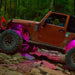 a Jeep driving on a rocky trail, with pink rock lights illuminating the trail.