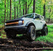White Ford Bronco in the forest with Amber LED Illuminated Letter Badges installed.