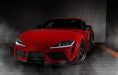 Three quarters view of a red Toyota Supra with white headlight DRLs.