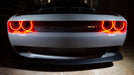 Front end of a grey Dodge Challenger with red LED headlight halo rings installed.