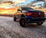 Three quarters view of a black Dodge Ram with red LED headlight halo rings installed.