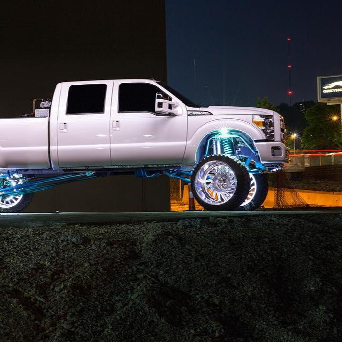 White Ford Superduty with white wheel rings and rock lights.