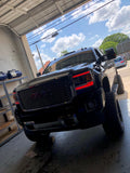 Front end of a GMC Sierra with red headlight DRLs.