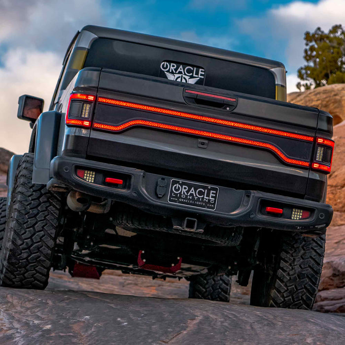 Rear view of a Jeep Gladiator JT, with multiple LED lighting products installed, including Flush Mount Tail Lights, High Powered Reverse Lights and Racetrack LED Tailgate Panel.