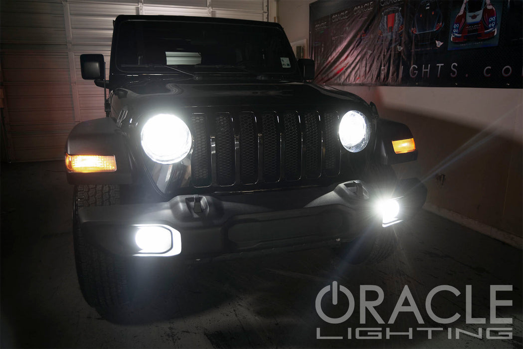 Black Jeep in a garage with super bright headlights and fog lights.